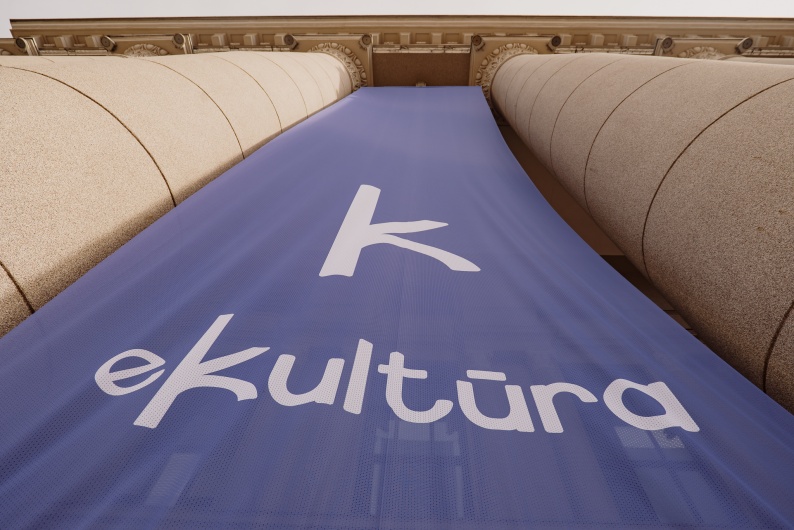 Tarp Nacionalinės bibliotekos kolonų plevėsuojanti vėliava su užrašu eKultūra