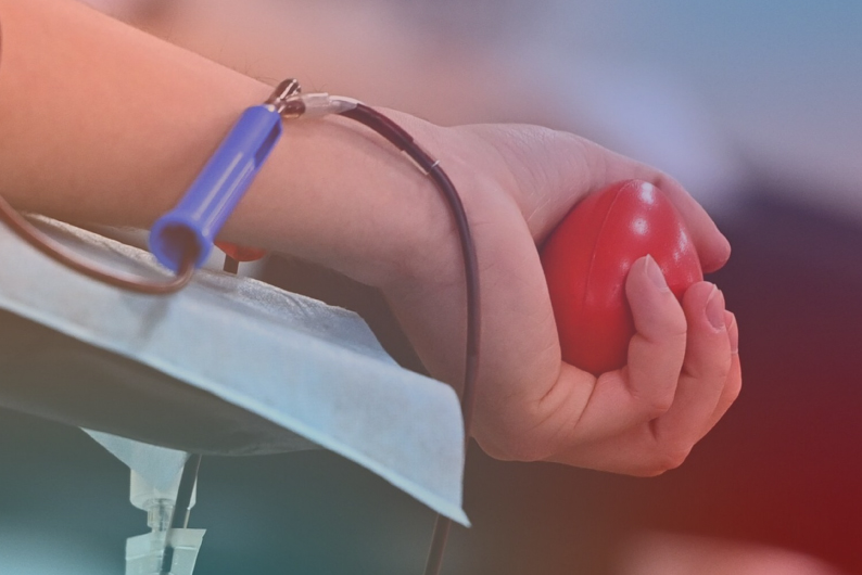 Pavaizduota raudoną kamuoliuką suspaudusi ranka, paruošta kraujo ėmimui.